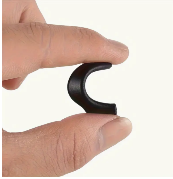Hand holding small black earphone accessory.